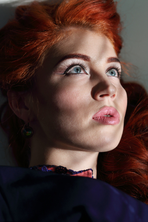 The shadow from the window falls on the face of a beautiful young woman with beautiful big eyes and long eyelashesの写真素材