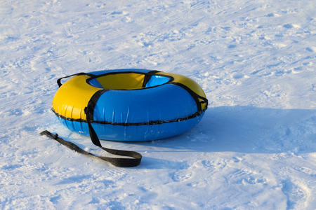 Yellow and blue new snowtube is on white snow at winter sunny dayの写真素材
