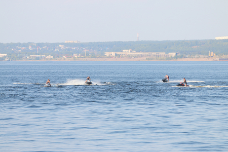 Four male and ride water motorcycles in a Sunny and warm day, leaving a water trailのeditorial素材