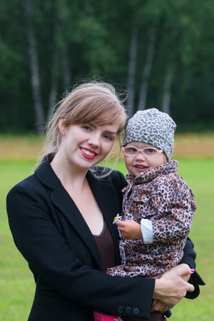 Young smiling woman holds little cute daughter outdoor at summer day, shallow dofの写真素材