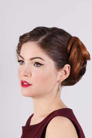 Pretty woman with hairdo, make-up and earrings in white studioの写真素材