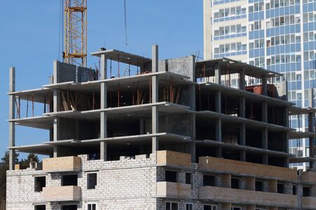 Unfinished high-rise apartment building, part of crane at sunny day