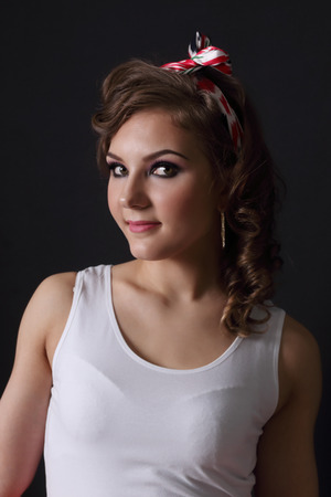 Pinup beautiful girl in white and with curly hair poses in black studioの写真素材