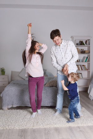 Happy handsome father, mother and little son dance in bedroom at homeの写真素材