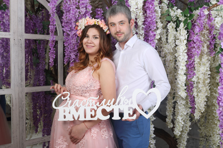 Man and pregnant woman hold text Happy together in studio with blooming wisteriaの写真素材