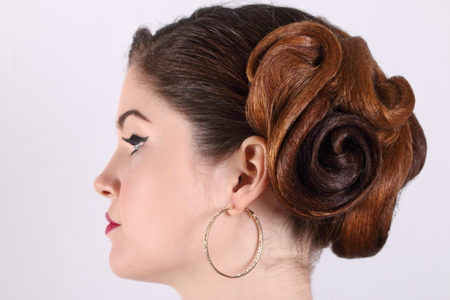 Beautiful woman with hairdo and earrings in studio, profile, focus on hairdoの写真素材