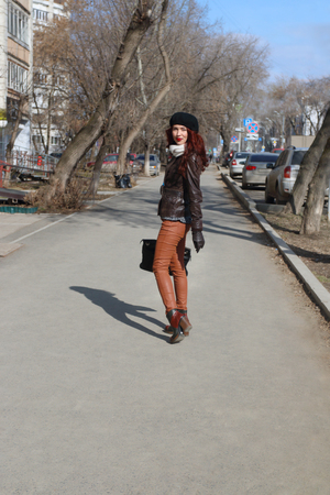 Beautiful girl in leather jacket and beret goes down street at sunny spring dayの写真素材