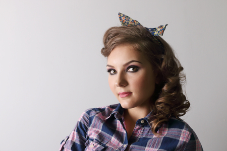 Pinup beautiful woman in checkered shirt and with bow in studioの写真素材