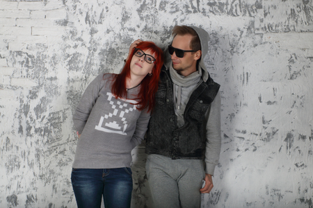 Young woman and man in sunglasses stand near white wall in studioの写真素材