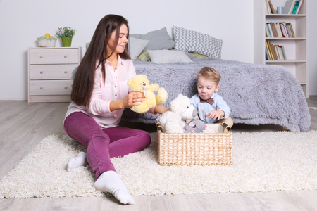 Little boy, mother play with toys in basket in cozy bedroom at homeの写真素材
