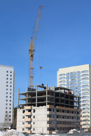 Unfinished high-rise building and working crane at sunny winter dayのeditorial素材