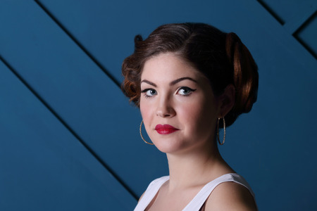 Beautiful girl with hairdo, make up in blue studio, close upの写真素材