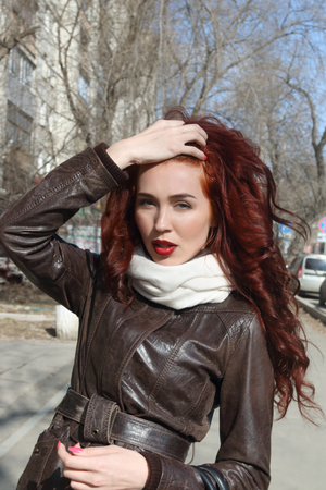 Girl with curly hair in jacket poses outdoor at sunny spring dayの写真素材
