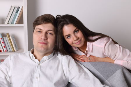 Woman and handsome man pose together on armchair in living roomの写真素材