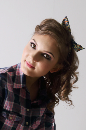 Pinup beautiful young woman in checkered shirt in grey studioの写真素材
