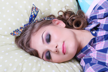 Pinup pretty girl in checkered shirt sleeps on soft pillows in studioの写真素材
