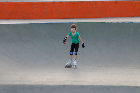 Happy girl roller skates on sport playground with ramps at summer dayの写真素材