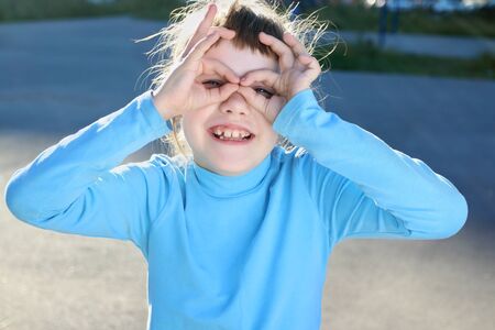 Girl depicts glasses on playground at summer sunny day, close up, shallow dofの写真素材