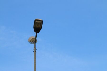 Modern lonely tall street light and bright blue sky with cloudsの写真素材