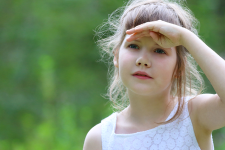Girl in white looks away at summer sunny day in park, close up, shallow dofの写真素材