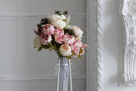 bouquet of peonies in vase against white wall in photo studioの写真素材