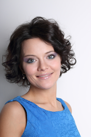 Smiling young brunette woman with clean skin and make-up on grey backgroundの写真素材