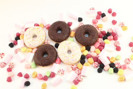 Donuts, many bright candies and marshmallows on white surface, top viewの写真素材