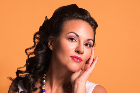 Pretty young brunette with hairdo and make up poses in studio, pin up style, close up portraitの写真素材