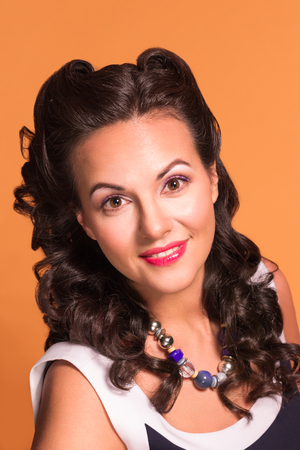 Pretty brunette with hairdo and make up poses in studio, pin-up style, close-up portraitの写真素材