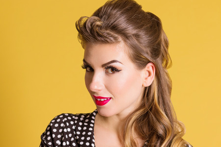 Beautiful woman with make up poses in yellow studio, pin up styleの写真素材