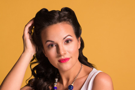 Pretty brunette with hairdo and make up poses in studio, pin up style, close up portraitの写真素材