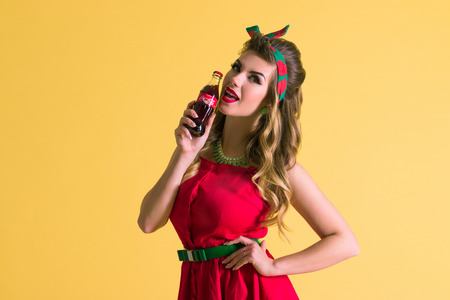 PERM, RUSSIA - DEC 25, 2017: Pretty girl (with MR) poses in studio with retro bottle of Coca-Cola,...