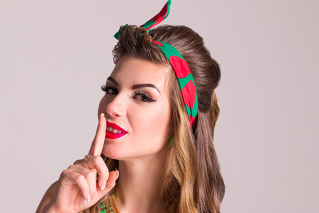 Woman with hairdo poses in studio, pin up style, close up portraitの写真素材
