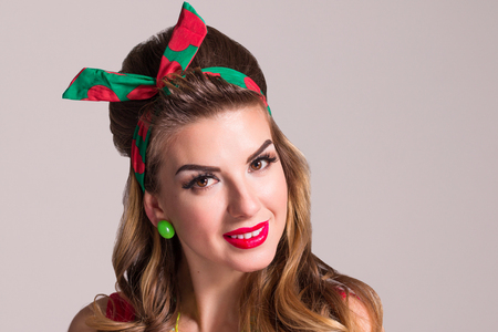 Young woman with hairdo and make up poses in studio, pin up style, close up portraitの写真素材