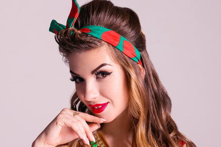 Pretty woman with hairdo poses in studio, pin up style, close up portraitの写真素材
