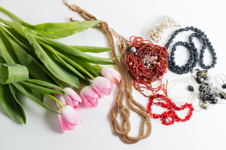 Pink fresh tulips with green leaves, different bijouterie on white - spring female thingsの写真素材