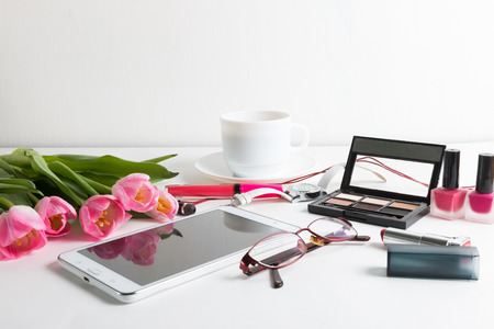 Pink tulips, tablet, cosmetics, wristwatch, notepad, cup of coffee, glasses - spring female thingsの写真素材