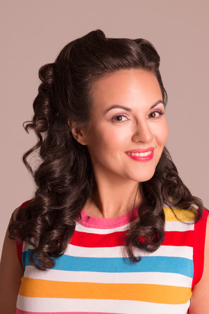 Happy young brunette with hairdo and make up poses in studio, pin-up styleの写真素材