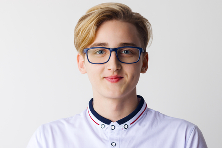 Handsome boy teenager in glasses and white shirt poses in white studioの写真素材