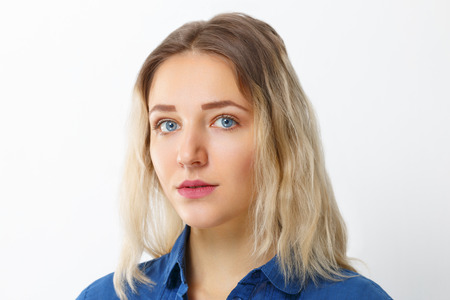 Pretty young girl  with make-up in blue shirt poses in studioの写真素材