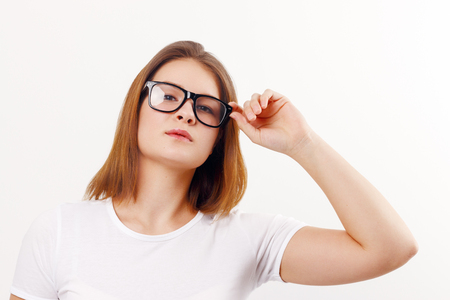 Beautiful happy girl teenager in glasses poses in white studioの写真素材