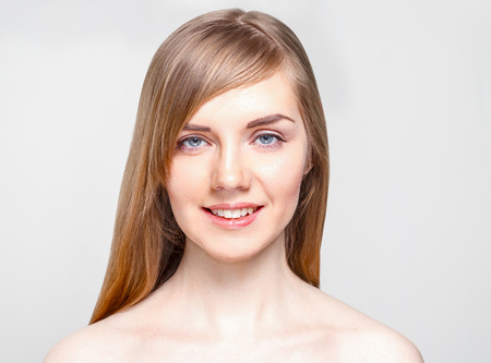 Pretty young woman with make-up smiles in studio, close up portraitの写真素材