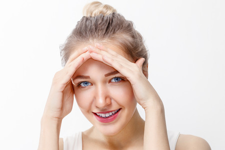 Pretty young girl with make-up shows home gesture in studio, close up portraitの写真素材