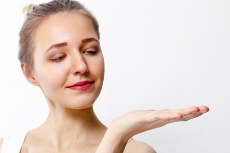 Pretty young girl with make-up shows palm in studio, close up portrait, focus on palmの写真素材