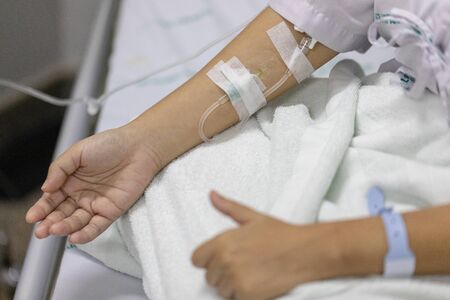Close up hand woman patient with injection Saline in hand and during lying rehabilitation beds the...