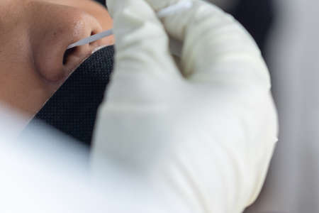 The doctor with PPE suit, Doctor is using a test coronavirus(covid-19) with the use of an ATK test kit by nasal swab.の写真素材