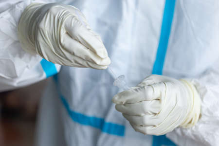 The doctor with PPE suit, Doctor is using a test coronavirus(covid-19) with the use of an ATK test kit by nasal swab.の写真素材