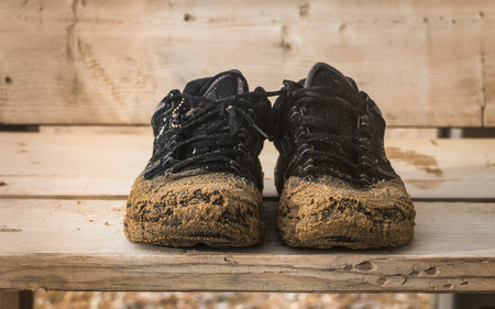 Front view of pair old black worn wet reliable pair of shoes are  on a benchの写真素材
