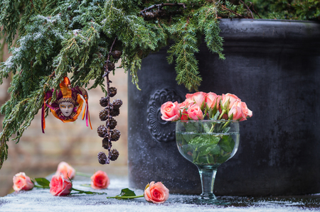 Christmas concept. Fir tree branch with decoration Venetian Harlequin and delicate roses on a table in the snowの写真素材