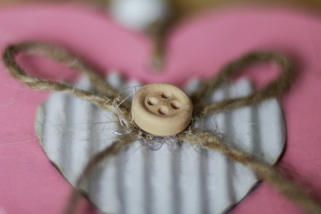 Heart handmade shapes with a button and rope on the pink background